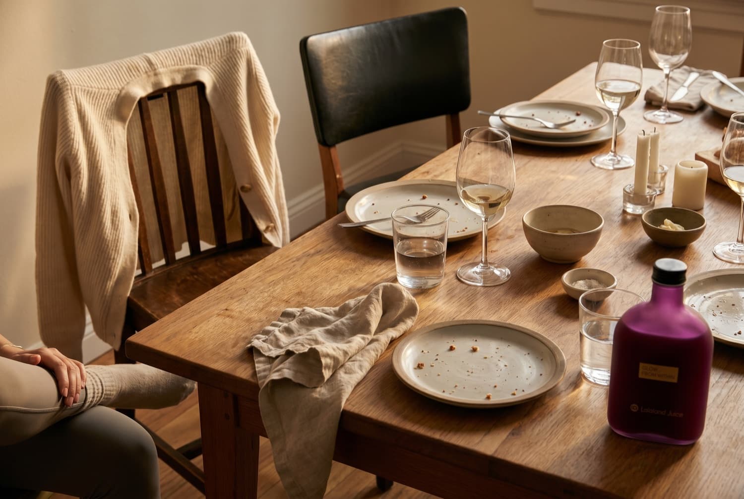 A table of friends, half-drunk glasses and a Lalaland bottle in warm light