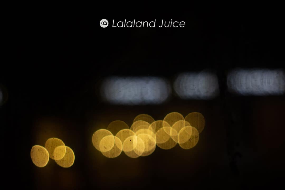 Warm golden lights blurred soft against the dark, the switched-on city seen gently — the Lalaland Juice mark set within.