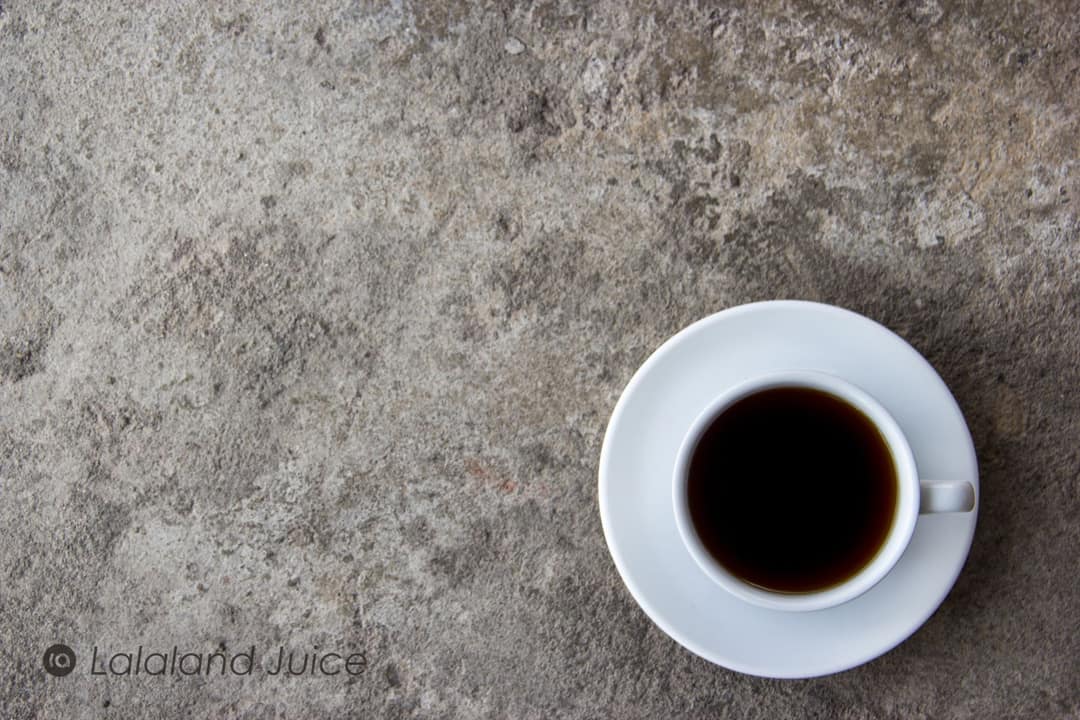 A quiet cup of black coffee on a stone counter, the morning in no hurry.