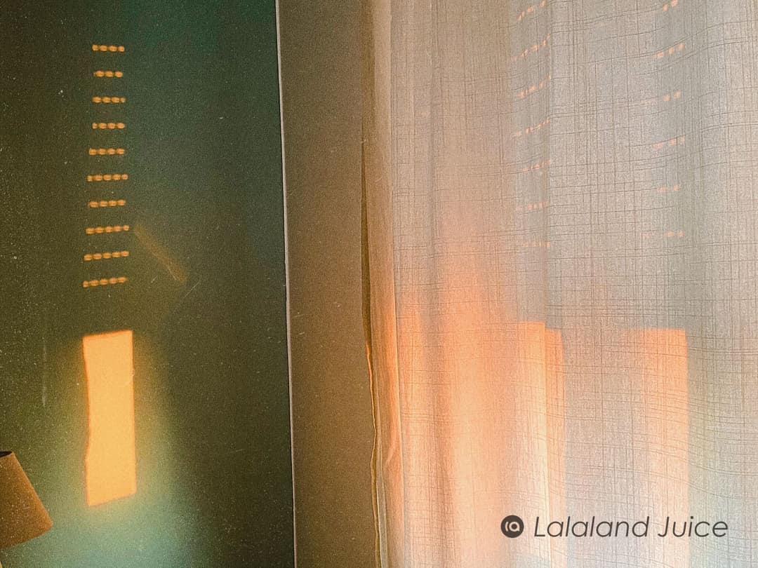 Evening sun through a sheer curtain, warm light resting on a green wall.