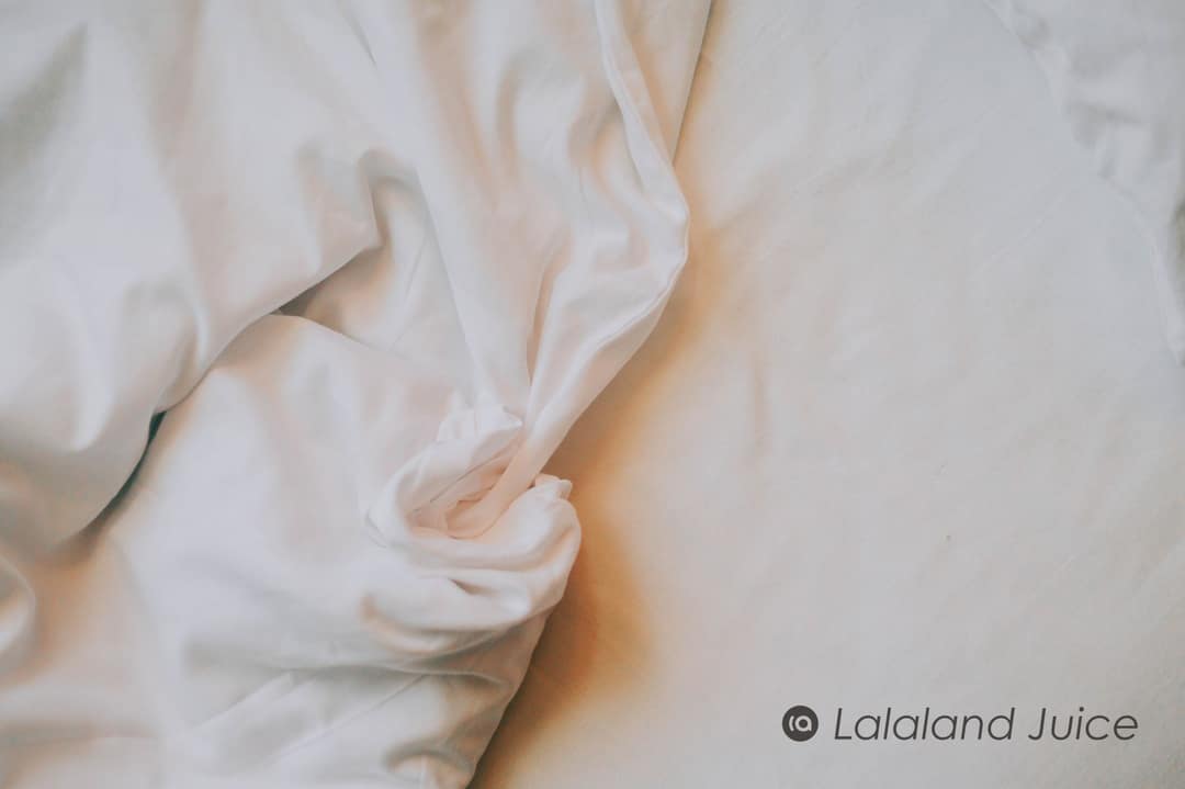 Crumpled white bedsheets in soft morning light.