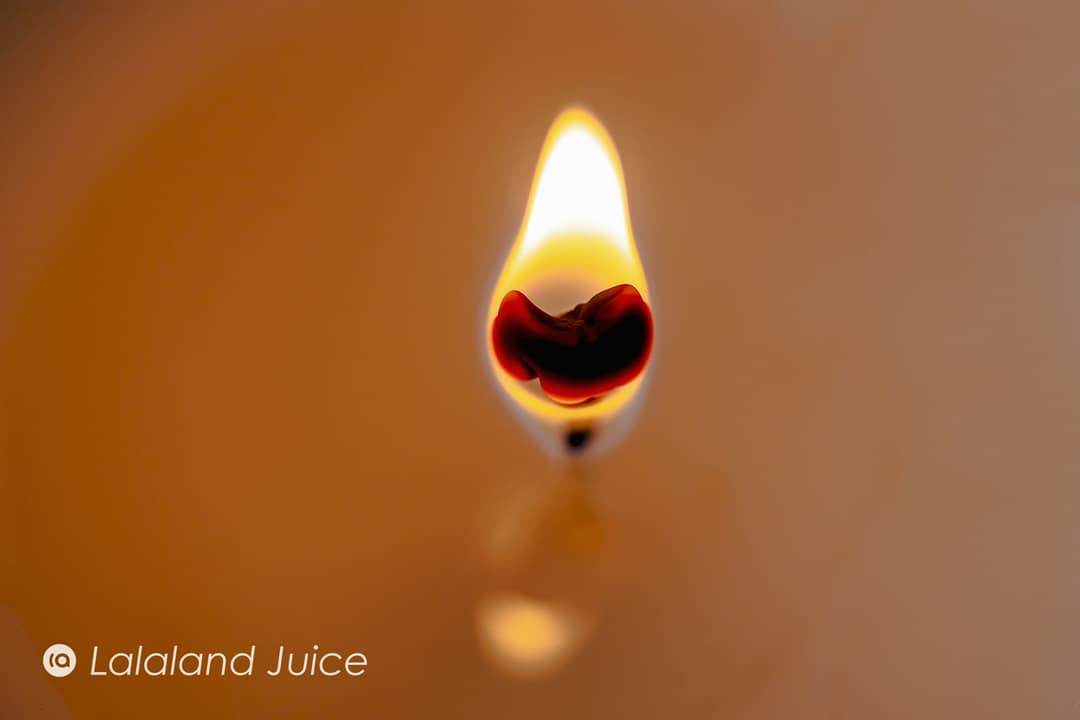 A single candle flame floating in warm amber light.